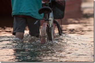 Biker on a flooded road during a flood caused by heavy rain, Thailand.