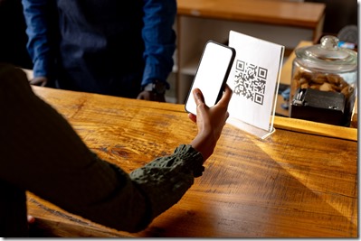 Hand of african american woman scanning qr code using smartphone in cafe