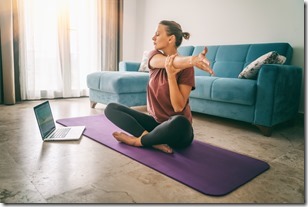 Attractive young woman doing yoga stretching yoga online at home. Self-isolation is beneficial, entertainment and education on the Internet. Healthy lifestyle concept