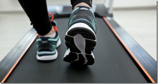 The woman's legs in new sneakers on the treadmill