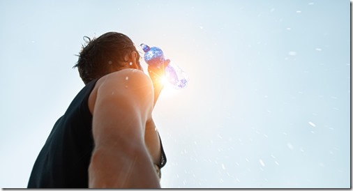 Man pouring water from plastic bottle on his head in hot day