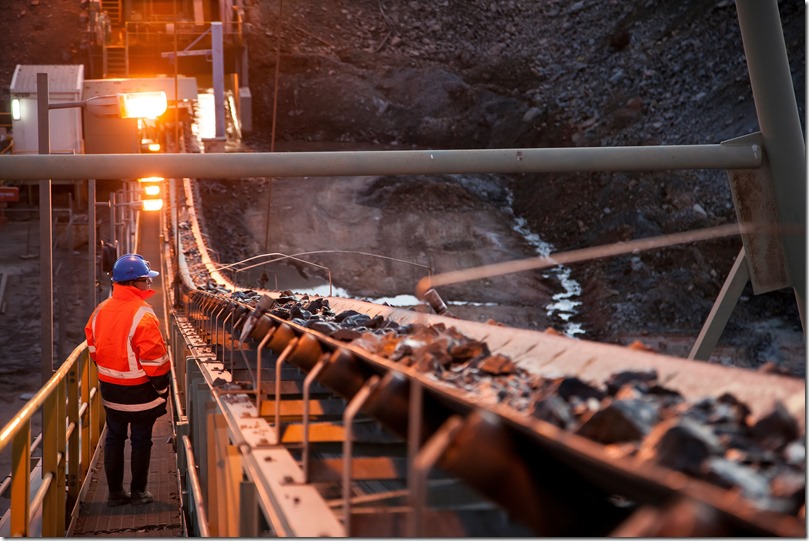 Nyngan Australia June 20th 2012 : Shallow depth of field image of a miner inspecting ore rocks on a conveyor in NSW Australia